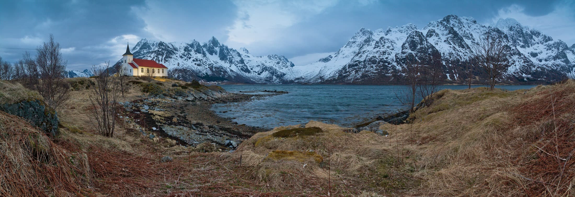 A small church beside a snow-lined Norwegian fjord