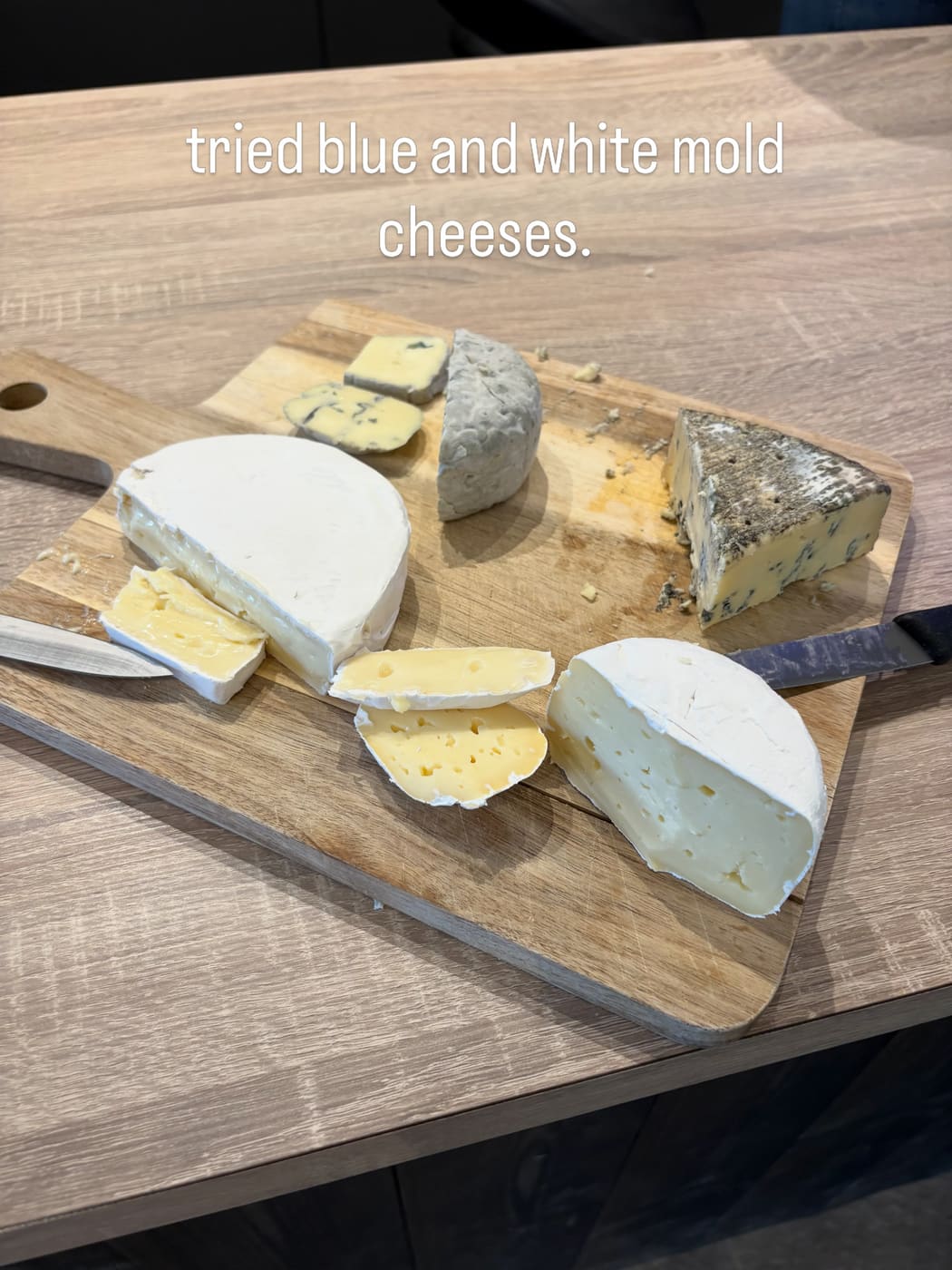 A wooden board of soft and blue cheeses